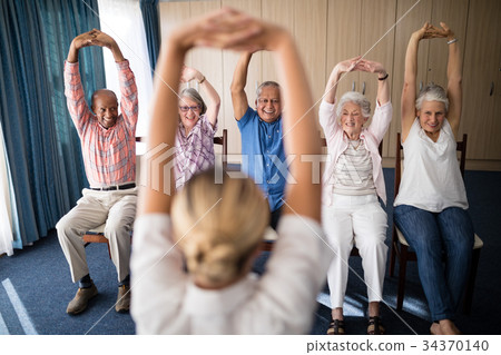 Cheerful senior men and women exercising with female doctor Cheerful senior men and women exercising with female doctor 34370140