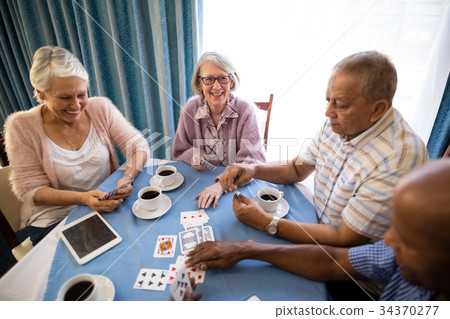 High angle view of senior friends playing cards 34370277