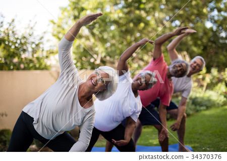 Portrait of smiling senior friends exercising with arms raised Portrait of smiling senior friends exercising with arms raised 34370376
