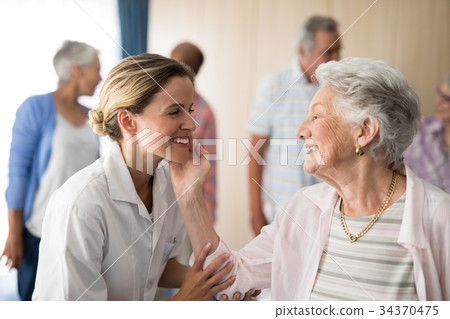 Senior woman touching smiling female doctor Senior woman touching smiling female doctor 34370475
