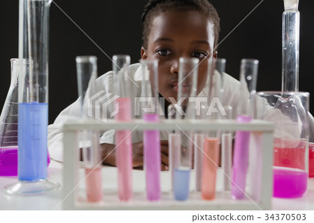 Schoolgirl doing a chemical experiment against black background 34370503