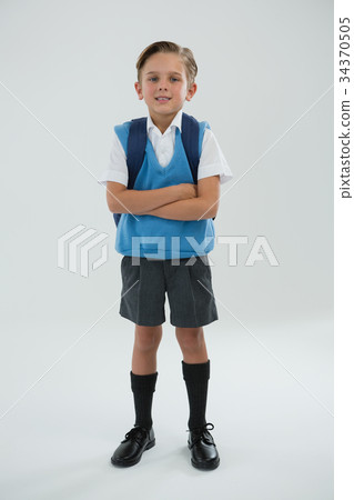 Portrait of cute schoolboy standing with arms crossed Portrait of cute schoolboy standing with arms crossed 34370505