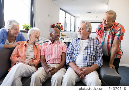 Smiling senior friends listening to man 34370548