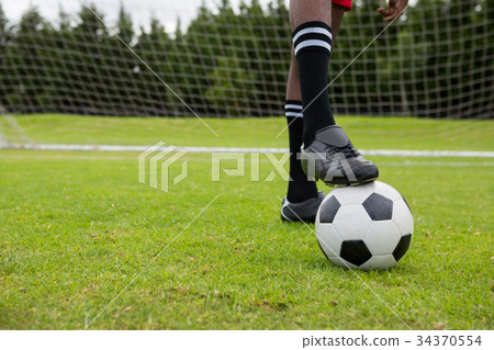 Low section of male soccer player with ball on field 34370554