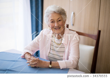 Portrait of smiling senior woman sitting with hands clasped 34370555