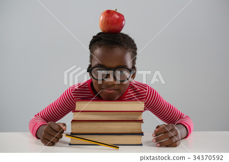 Schoolgirl leaning on books stack against white background 34370592