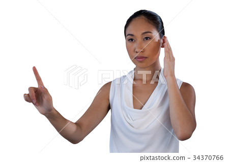 Serous businesswoman pretending to answer call while touching invisible interface 34370766