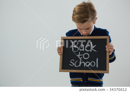 Schoolboy holding slate with text against white background Schoolboy holding slate with text against white background 34370812