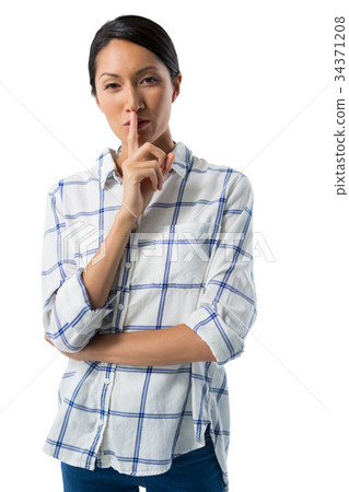 Portrait of woman standing with finger on lips 34371208