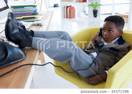 Full length of boy imitating as businessman talking on landline phone 34371396