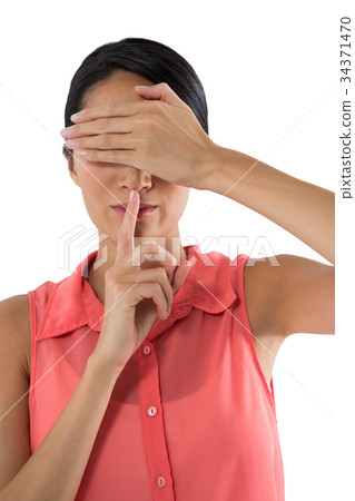 Woman covering her eyes with finger on lips against white background Woman covering her eyes with finger on lips against white background 34371470