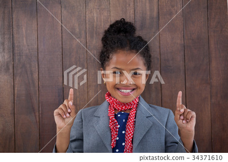 Portrait of smiling girl pretending as businesswoman pointing upwards 34371610