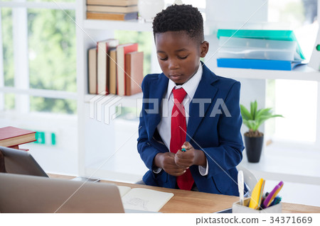Businessman holding pen while sitting at desk 34371669