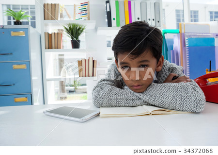 Bored businessman looking away while leaning on desk 34372068