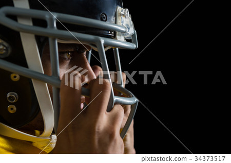 American football player holding a head gear on his head 34373517