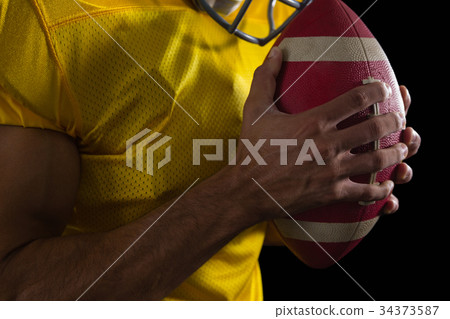 American football player holding a ball with both his hands 34373587