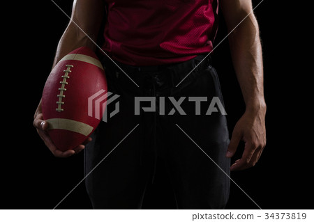 American football player holding a ball in one hand 34373819
