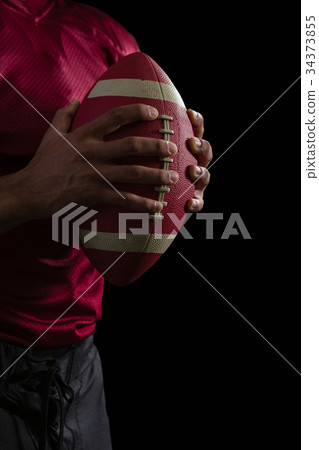 American football player holding a football with both his hands American football player holding a football with both his hands 34373855