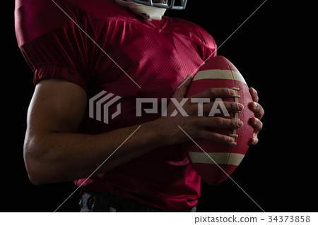 American football player holding a ball in one hand 34373858