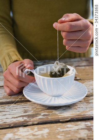 Mid section of woman dipping tea bag in cup 34373868