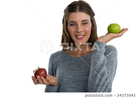 Portrait of young woman showing apples Portrait of young woman showing apples 34373945