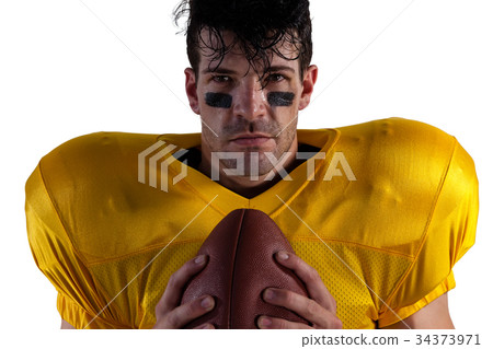 Portrait of determined American football player holding ball Portrait of determined American football player holding ball 34373971
