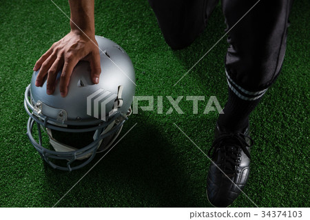 American football player resting his hands on head gear 34374103