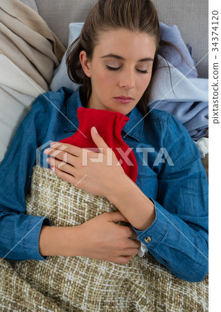 Directly above shot of woman with hot water bottle while sleeping 34374120
