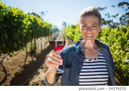 Portrait of female vintner holding glass of wine 34374233