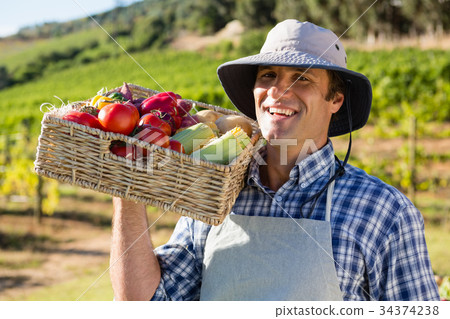 Portrait of happy farmer holding a basket of fresh vegetables Portrait of happy farmer holding a basket of fresh vegetables 34374238