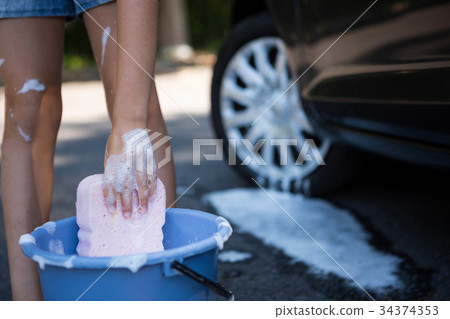 Teenage girl washing a car on a sunny day 34374353