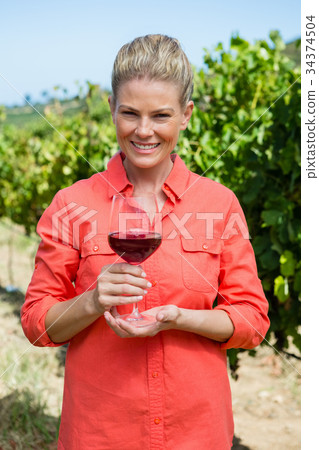 Portrait of female vintner holding glass of wine 34374504