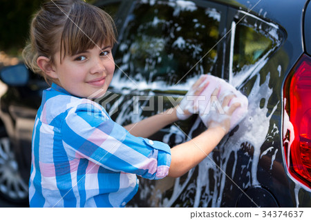 Teenage girl washing a car on a sunny day 34374637