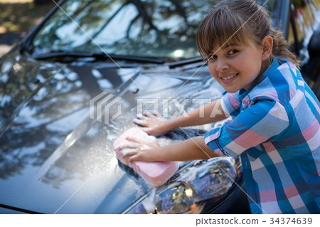 Teenage girl washing a car on a sunny day 34374639