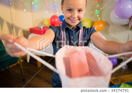 Girl holding a gift bag during birthday party hat 34374791