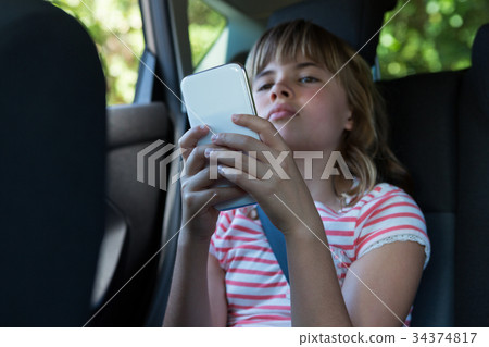Teenage girl using mobile phone in the back seat of car Teenage girl using mobile phone in the back seat of car 34374817