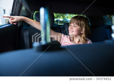 Teenage girl sitting in the back seat of car 34374852