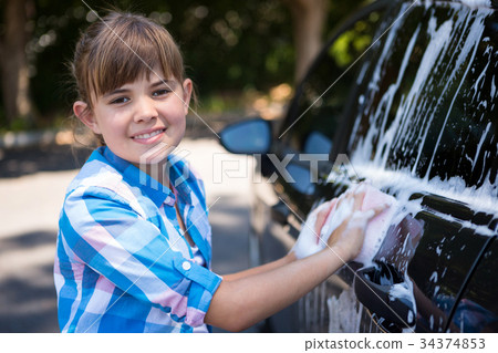 Teenage girl washing a car on a sunny day 34374853