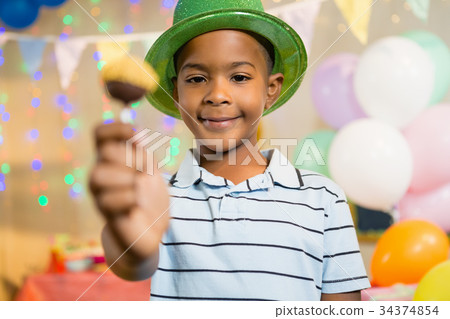 Portrait of happy boy holding lollipop during birthday party 34374854