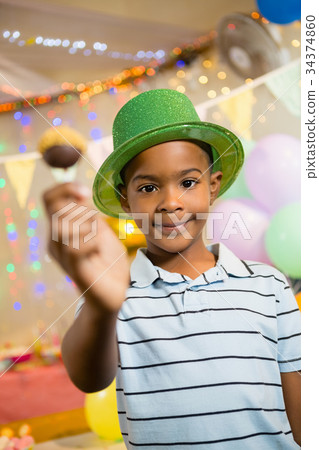 Portrait of happy boy holding lollipop during birthday party Portrait of happy boy holding lollipop during birthday party 34374860