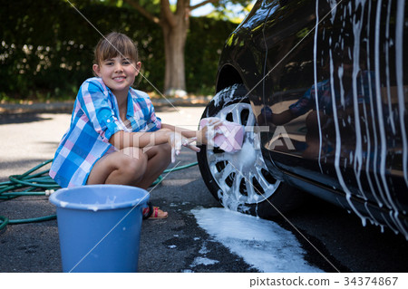 Teenage girl washing a car on a sunny day 34374867