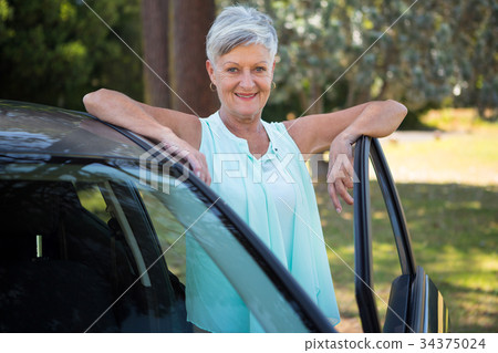 Senior woman standing beside a car 34375024