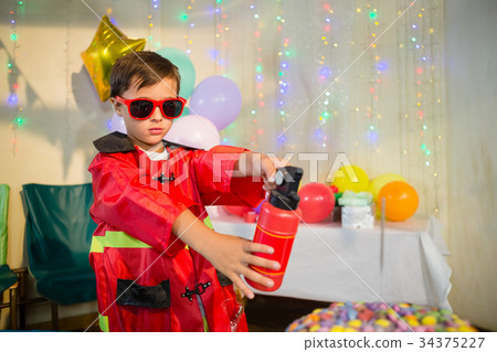 Cute boy pretending to be a fireman during birthday party Cute boy pretending to be a fireman during birthday party 34375227
