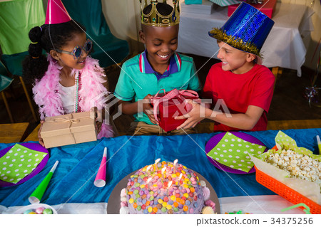 High angle view of friends giving gifts to boy High angle view of friends giving gifts to boy 34375256