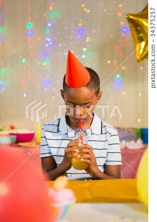 Boy drinking juice during birthday party Boy drinking juice during birthday party 34375257