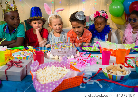Children looking at birthday cake on table Children looking at birthday cake on table 34375497