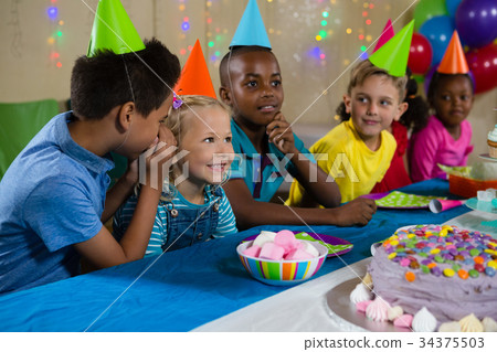 Boy whispering to girl while sitting with friends Boy whispering to girl while sitting with friends 34375503
