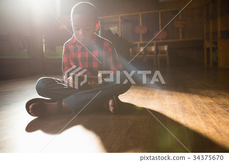 Boy sitting on wooden floor using digital tablet 34375670
