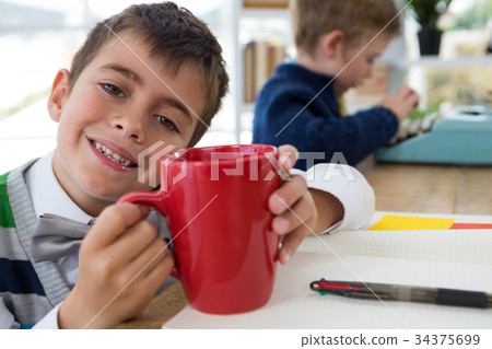 Boy as business executive holding coffee mug in office 34375699