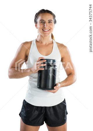 Portrait of smiling female athlete holding supplement jar Portrait of smiling female athlete holding supplement jar 34375744